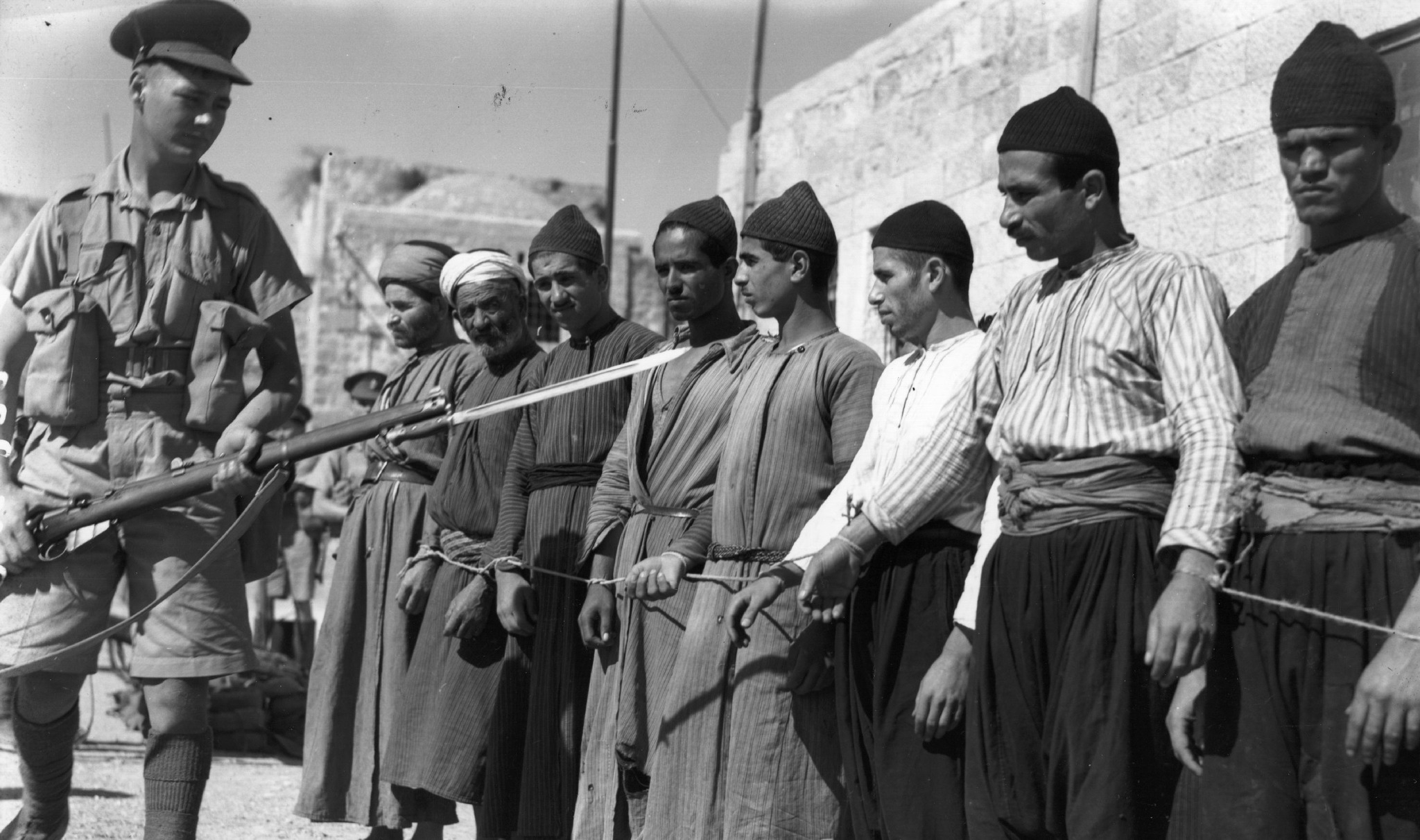 A British soldier guards Palestinian prisoners in Jerusalem, 1938 (Photo: Fox Photos / Getty)