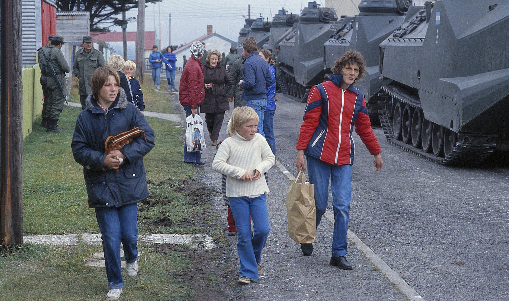 Los isleños de las Malvinas caminan junto a las tropas argentinas en Puerto Stanley, abril de 1982. (Foto: Rafael Wollmann / Getty)