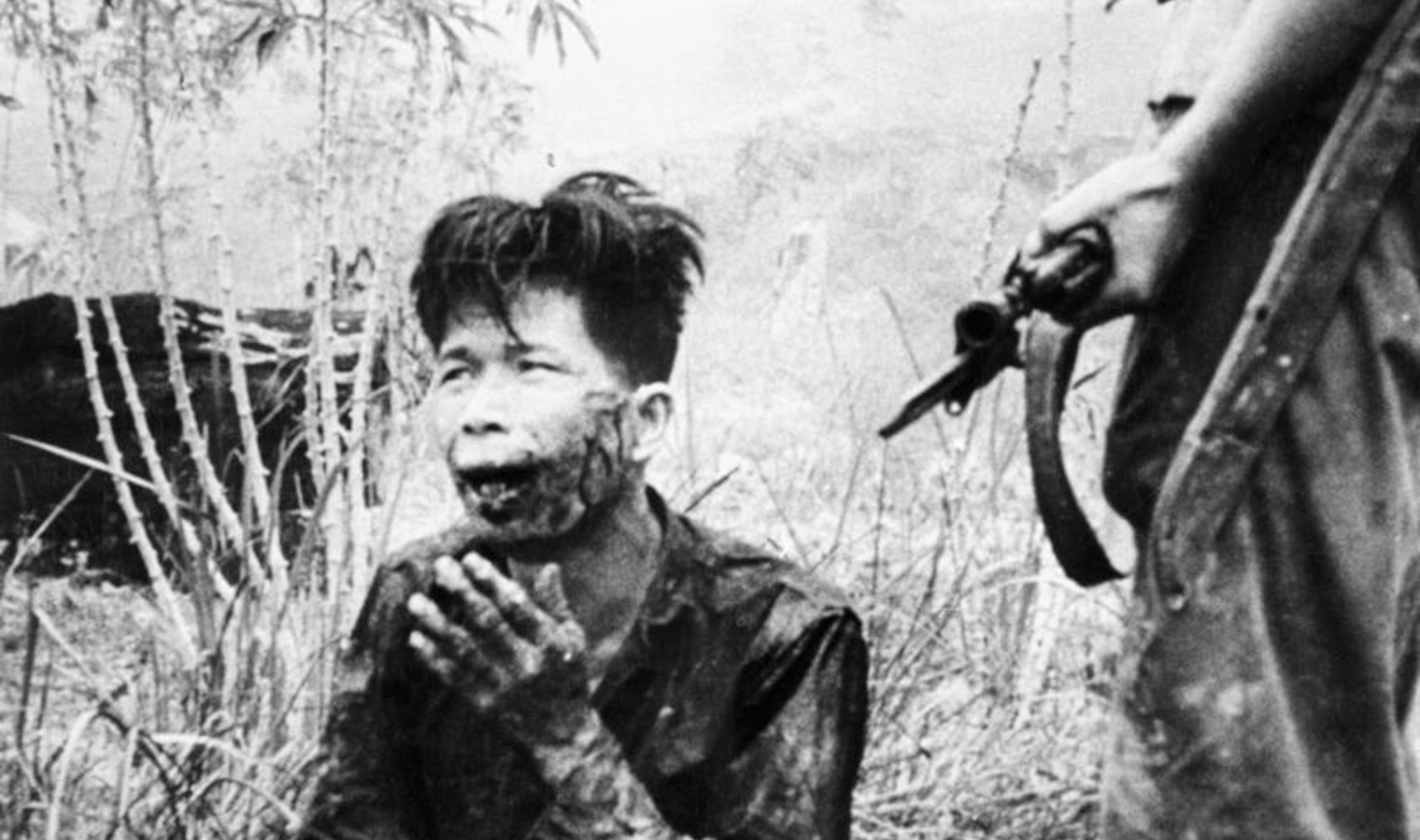 A wounded man is held at gunpoint by British forces in Malaya. (Photo: Ministry of Information)