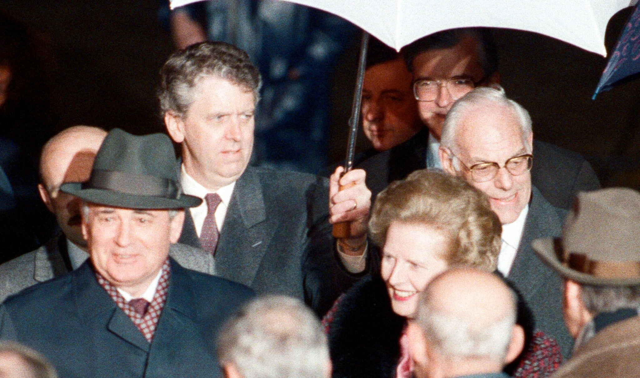 Charles Powell holds an umbrella for Margaret Thatcher on a foreign engagement. (Photo: Bill Rowntree / Mirrorpix / Getty)
