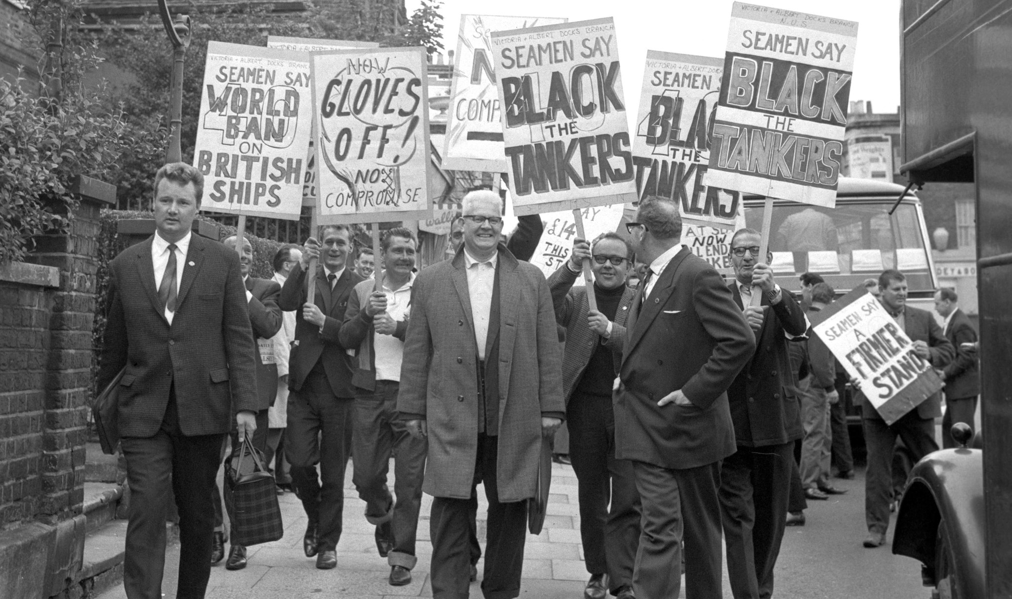A black and white image showing members of the National Union of Seamen marching with placards. Bearing placards calling for a world ban on British ships and to 'black the tankers' are members of the Victoria and Albert Docks Branch of the National Union of Seamen. They arrived at the Union's Clapham headquarters, where the 48-man Executive was meeting for the first time since the 62,500 Union members were called out on strike on May 16th.