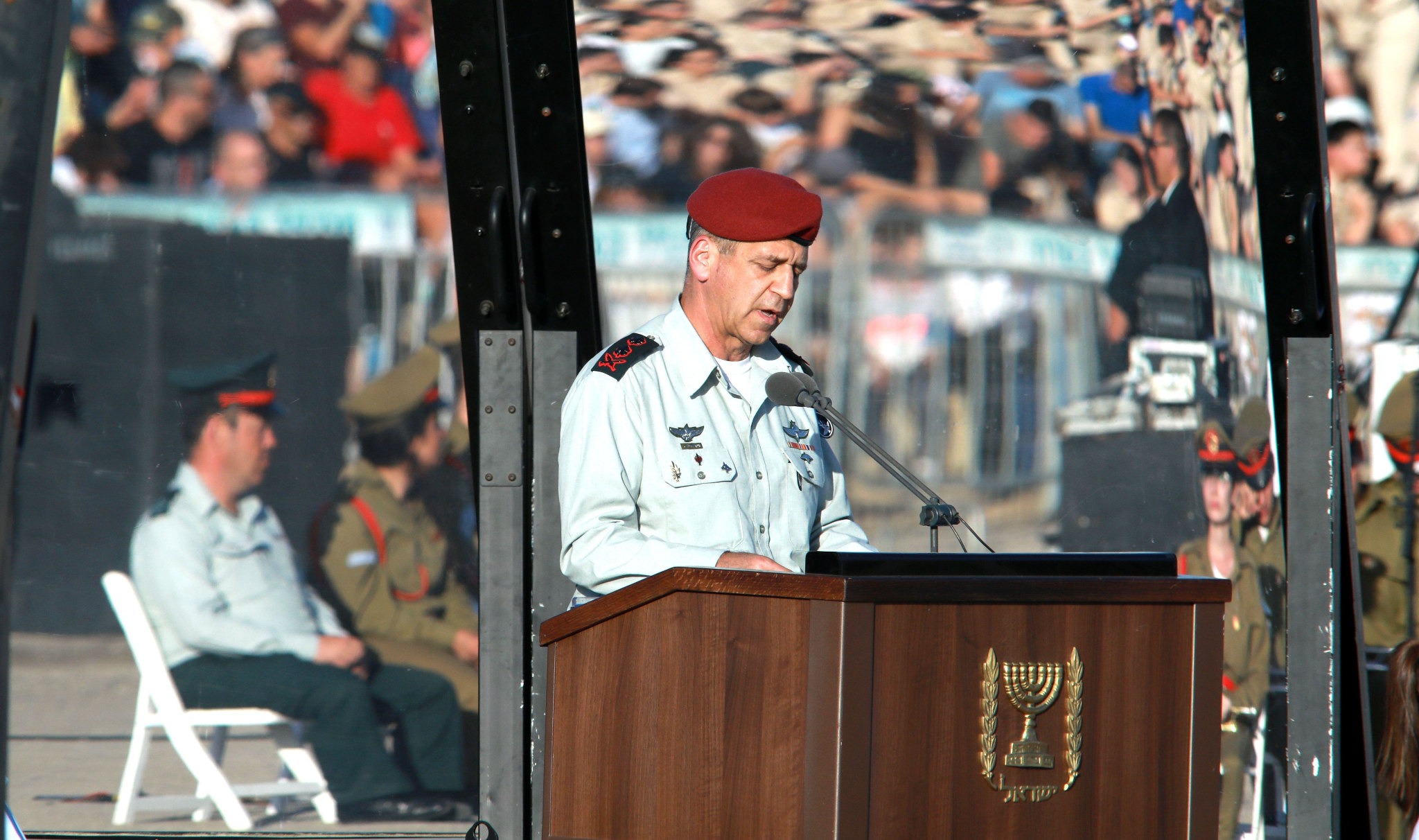 General Aviv Kohavi gives a speech from a brown podium while wearing a red beret