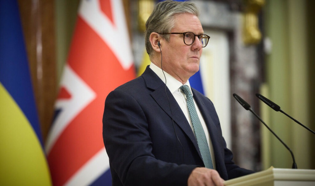 Keir Starmer stands at a podium with British and Ukrainian flags behind him.